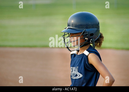 Girl baseball player wearing a protective helmet with a face guard Stock Photo