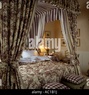 Four poster bed with fabric canopy and matching quilted bed cover Stock Photo
