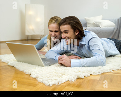 Couple lying on floor, using laptop Stock Photo