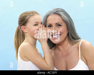 Granddaughter wispering in grandmothers ear, portrait Stock Photo