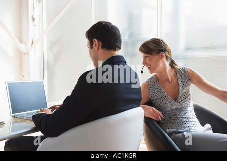 Business man working on laptop, female colleague with headset Stock Photo