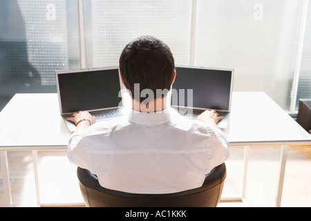 Business man using two laptops, back view Stock Photo