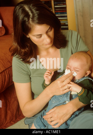 Baby boy with a cold having his nose wiped by his mother, coronovirus covid virus symptom symptoms U.K. UK Stock Photo