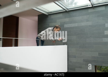 Man using a mobile phone while leaning on banister Stock Photo