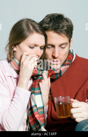 Young couple with a cold drinking tea