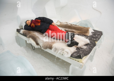A tourist lying on a bed in a bedroom of the Jukkasjarvi ice hotel Stock Photo