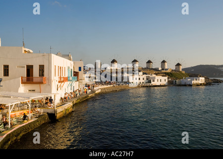People sitting in restaurants and bars directly at sea windmills in background Little Venice Mykonos Town Mykonos Greece Stock Photo