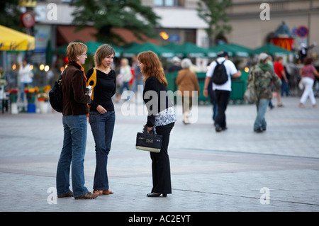 three young local women female friends share gossip in rynek glowny town square krakow Stock Photo