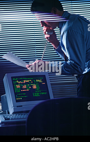 Businessman on phone in office looks over document Stock Photo