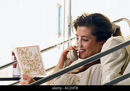 Caucasian female patient reading get well card and talking on telephone Stock Photo