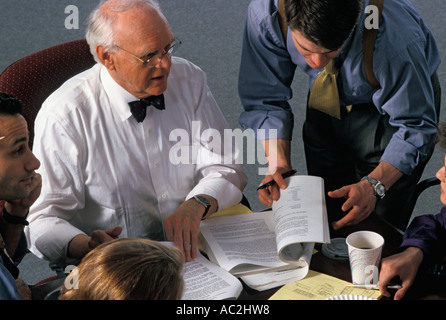 Young Caucasian businessman assists mature Caucasian businessman during meeting Stock Photo