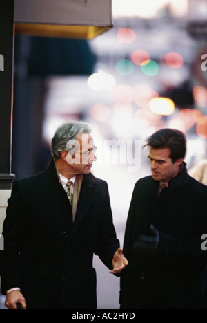 Caucasian businessmen walking and talking on street Stock Photo