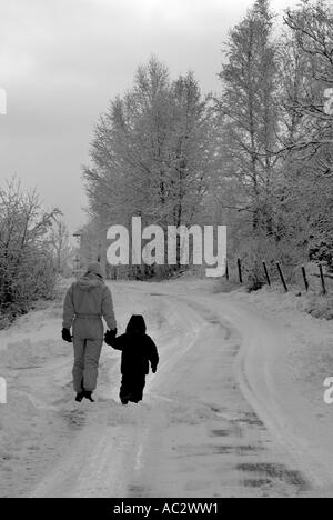 France french alps selonnet mother and three years old girl walking on a snowy road Stock Photo