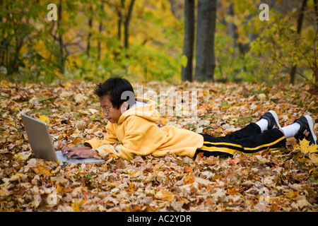 Young Asian boy doing homework on laptop Stock Photo