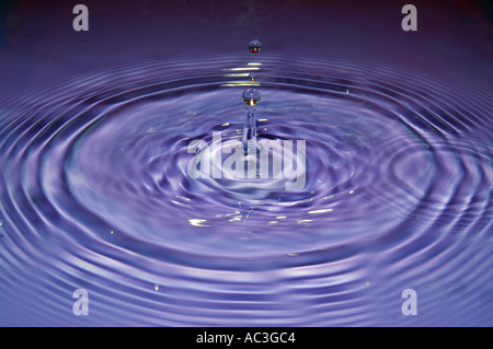 Water drop impact frozen mid splash with ripples and droplets Stock Photo