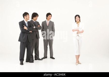 Three businessmen looking at businesswoman Stock Photo