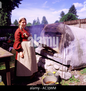 Woman Re-enactor baking Bread in Old Outdoor Bake Oven at Fort Langley National Historic Site, BC, British Columbia, Canada Stock Photo