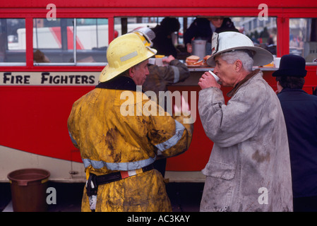Firefighters / Firemen talking while taking a Coffee Break after fighting a Fire Stock Photo