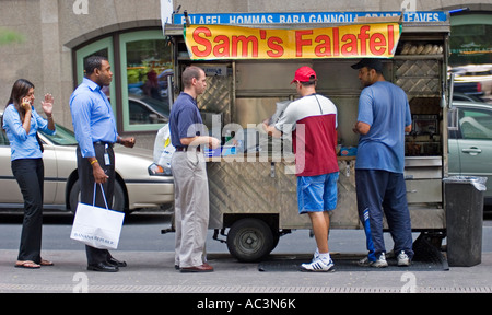 A line of people wait to buy food from a food stand in New York City, New York Stock Photo