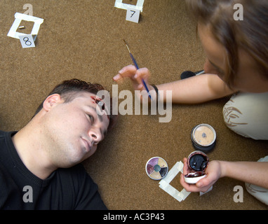 Make up Artist working on and actor in the set of a movie applying fake blood Stock Photo