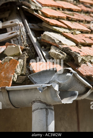 Damaged French red tile hipped roof with broken lead guttering, broken red tiles and exposed roof timbers close up in saint valery sur somme france eu Stock Photo