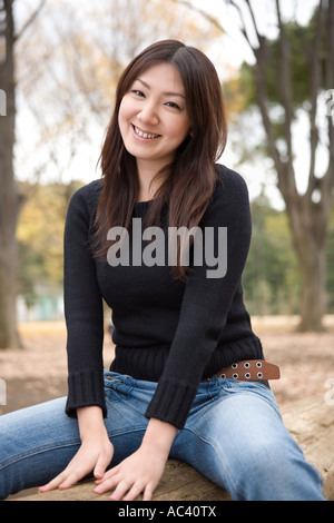 Young woman sitting on log Stock Photo