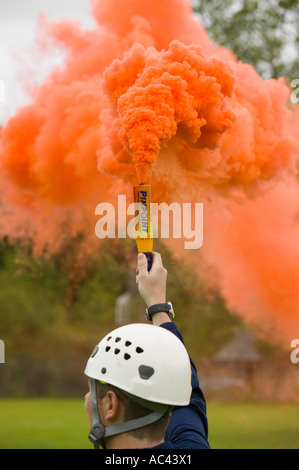 a mountain rescue team member uses a flare to attract and RAF sea King Helicopter to the landing site, Ambleside, Lakle district Stock Photo
