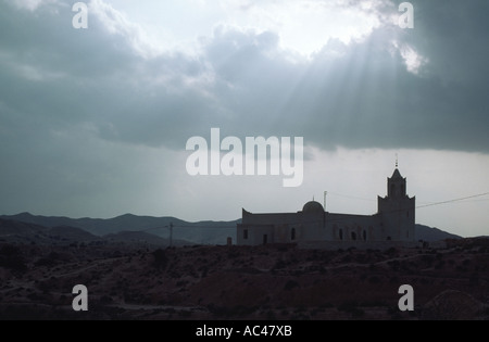 Sun breaking through clouds to light up the mosque in the village of Matmata southern Tunisia North Africa Stock Photo