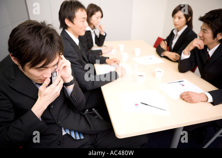 Young businessman using mobile phone during meeting Stock Photo