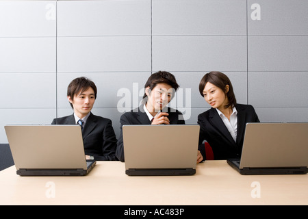 Three young business people using computers Stock Photo