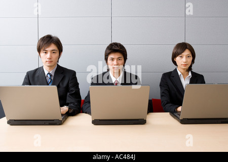 Three young business people using computers Stock Photo