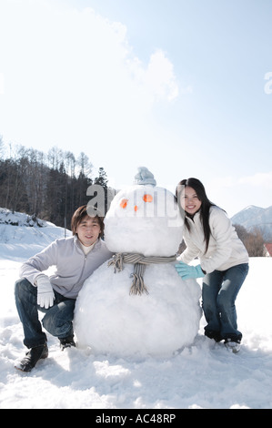 Young couple with snowman Stock Photo