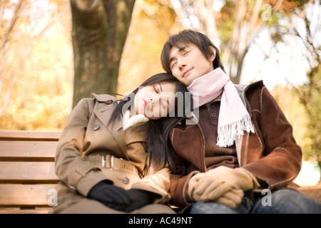Young couple sitting and sleeping on bench Stock Photo