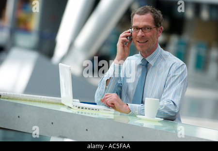 business man working with mobile phone and laptop computer in an airport terminal Stock Photo