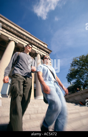 Two young adult students walking down steps with columns in background Two young adult students walking down steps columns Stock Photo