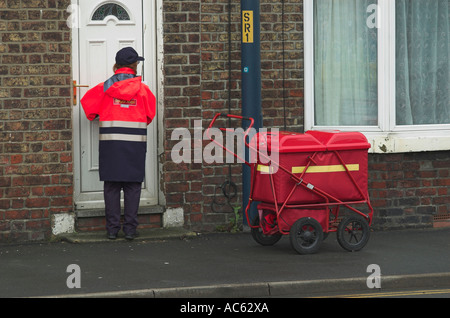 Post person delivering the daily post Mail in Filey North Yorkshire England United Kingdom U K Great Britain Stock Photo