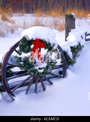 Bureau County, IL: Holiday decorations and fresh snow on a wagon wheel and split rail fence Tall grass prairie and winter fores Stock Photo