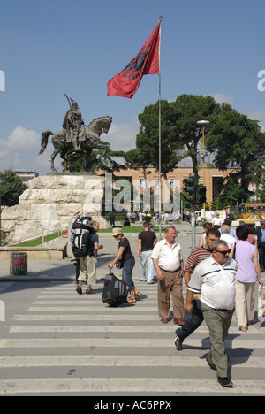 Tirana Republic of Albania equestrian statue of Skanderbeg & people crossing road in Skanderbeg Square on pedestrian crossing Albanian national flag Stock Photo