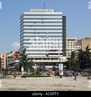 Republic of Albania multi storey exterior facade of Tirana International Hotel building people walking across pot holed part of Skanderbeg Square Stock Photo