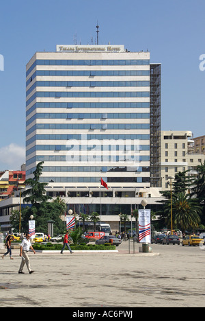 Republic of Albania multi storey exterior facade of Tirana International Hotel building people walking across pot holed part of Skanderbeg Square Stock Photo