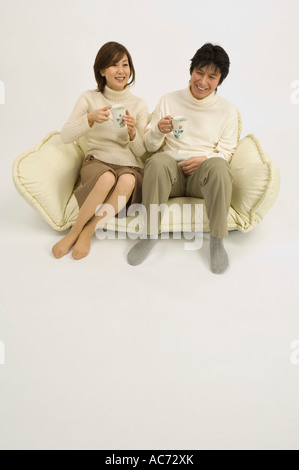Couple drinking coffee on sofa Stock Photo