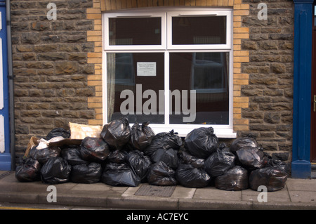 Piles of black bin bags outside a terraced house awaiting collection by the local authority Aberystwyth Wales UK Stock Photo