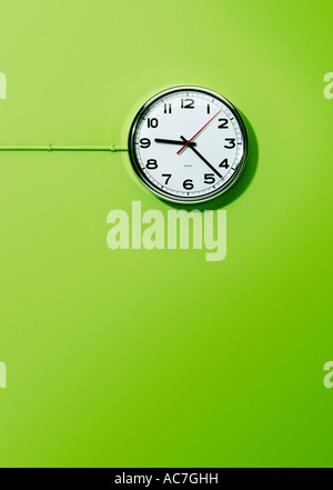 Wall mounted electric office clock against a lime green background Stock Photo