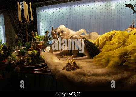 lady mannequin relaxing  in elegant pose on dinner table  in Harrods department store christmas window display london UK Stock Photo