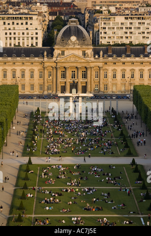 Groups of people picnicking on the grass of Parc du Champ de Mars in in the shadow of the Eiffel Tower at sunset Paris France Stock Photo