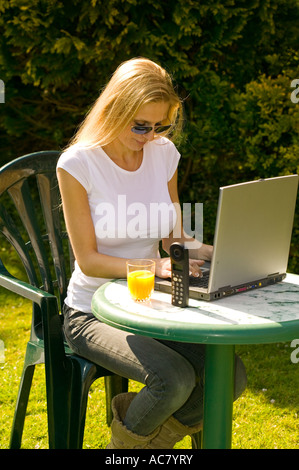 woman working from home, in her garden, using a laptop Stock Photo