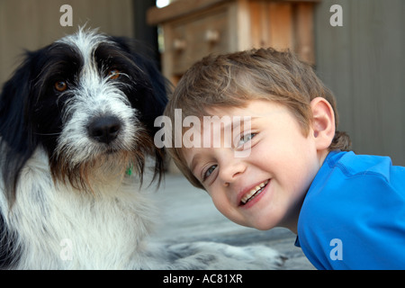 boy 7 laying with his pet dog on the deck Stock Photo