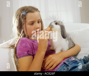girl feeding lop-eared dwarf rabbit Stock Photo