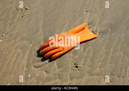 Discarded orange glove on the beach at Camber Sands Rye East Sussex England Stock Photo