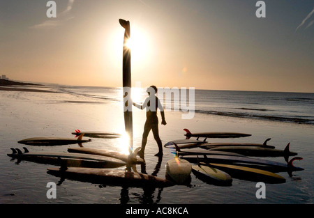 Surfboarder on Brighton beach with collection of vintage old boards Stock Photo